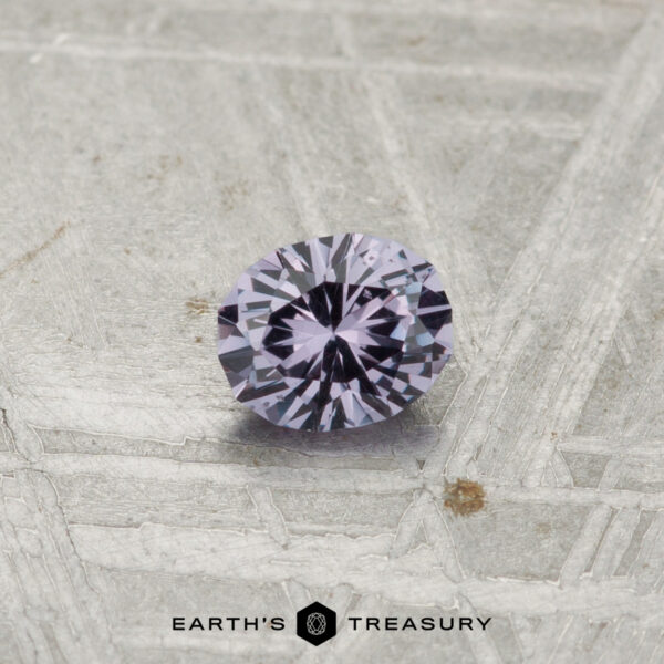A 0.28-carat color-change garnet, round and faceted, is displayed on a textured gray surface with "Earth's Treasury" at the bottom.