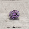 A 0.30-carat color-change garnet with a round, faceted cut rests on a textured gray surface featuring the "Earth's Treasury" logo at the bottom.