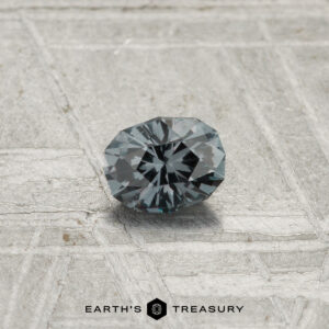 A 0.30-carat Color-Change Garnet is showcased on a textured gray surface with "EARTH'S TREASURY" displayed at the bottom.