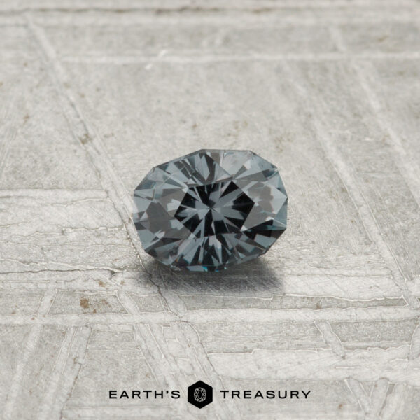 0.30-Carat Color-Change Garnet A 0.30-carat Color-Change Garnet is showcased on a textured gray surface with "EARTH'S TREASURY" displayed at the bottom.