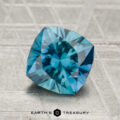 A 1.91-carat square cushion-cut blue Montana sapphire is displayed on a textured gray surface with "Earth's Treasury" below.