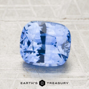 A 2.37-carat sky blue Ceylon sapphire (heated), faceted in a cushion cut, is displayed on a textured light surface with the "Earth's Treasury" logo at the bottom of the image.