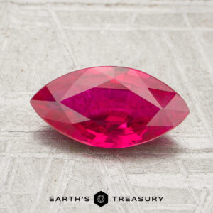 A 1.22-carat marquise-cut deep pink ruby is displayed on a textured surface with the words "Earth's Treasury" beneath it.
