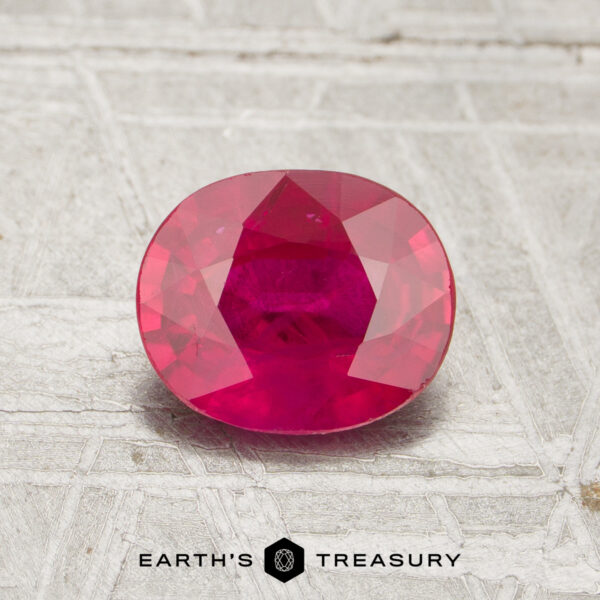 1.16-Carat Ruby A 1.16-carat, oval-cut vivid red ruby rests on a textured light surface with "Earth's Treasury" below it.