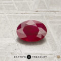 A 0.80-carat oval-cut ruby is displayed on a textured, light-colored surface with "EARTH'S TREASURY" at the bottom.