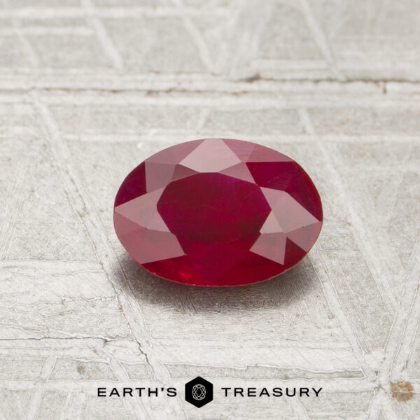 0.80-Carat Ruby A 0.80-carat oval-cut ruby is displayed on a textured, light-colored surface with "EARTH'S TREASURY" at the bottom.