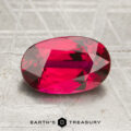 A 2.07-carat oval-cut deep red ruby is displayed on a textured surface, with "EARTH'S TREASURY" written below the gemstone.