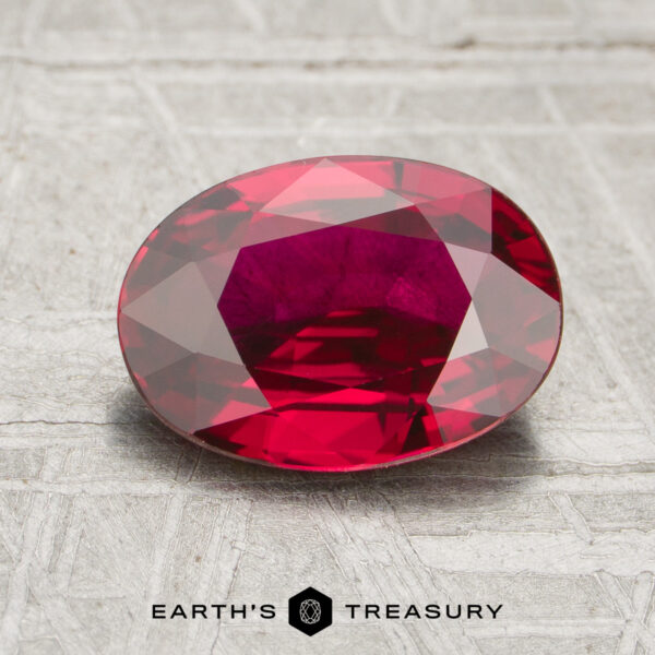2.21-Carat Ruby A 2.21-carat ruby with an oval faceted cut is displayed on a textured gray surface, with the text "EARTH'S TREASURY" below.