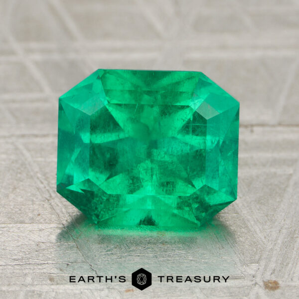 2.12-Carat Rich Green Colombian Emerald (Oiled) A 2.12-carat rich green Colombian emerald (oiled), cut in a rectangular faceted shape, displayed on a textured surface with the text "Earth's Treasury" below.