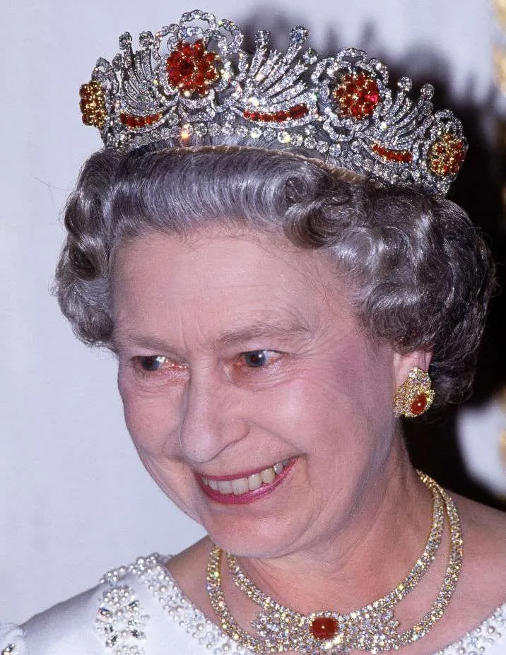 An older woman with gray hair is smiling in formal attire, wearing the tiara-1200-BW, pearl earrings, and a matching necklace.