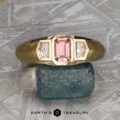 The "Firenze" ring, expertly crafted in 18k yellow gold, features a 0.61-carat Montana sapphire center stone accented by two clear side stones. The ring is displayed on a rough blue-green mineral, with the "Earth's Treasury" text below.