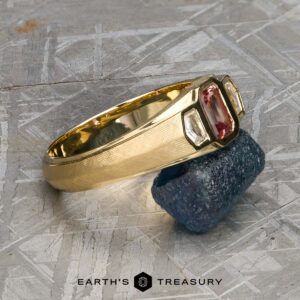 Presenting the "Firenze" ring in 18k yellow gold, showcasing a 0.61-carat Montana sapphire at its center and accented by two rectangular clear stones. Displayed elegantly atop a rough dark blue crystal, this striking piece is ready to ship.
