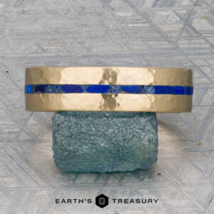 A "Stacked from 52 images. Method=B (R=14,S=2)" gold ring with a hammered finish and a striking blue inlay sits on a rough green stone, displayed on a textured gray surface with the "Earth's Treasury" logo below.