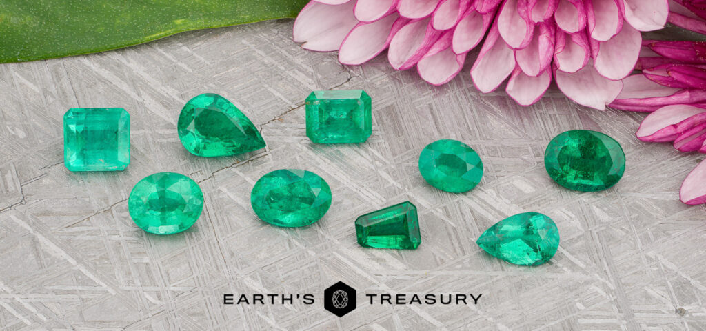 Ten green emerald gemstones of various shapes are displayed on a textured surface, accompanied by pink flowers and a green leaf in the background, creating an enchanting scene. The "Stacked from 47 images. Method=B (R=7,S=2)" logo appears at the bottom.