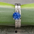 Introducing Stacked from 16 images. Method=B (R=7, S=2): a round blue gemstone ring with two diamond-accented silver bands, elegantly displayed against a green and gray background.