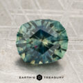 A 2.71-carat heated Montana sapphire in blue-green hues is displayed on a textured, patterned surface with the text "EARTH'S TREASURY" at the bottom.