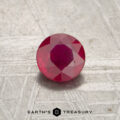 A 0.55-carat faceted red Mozambique ruby (heated) sits on a textured light surface with "EARTH'S TREASURY" at the bottom.