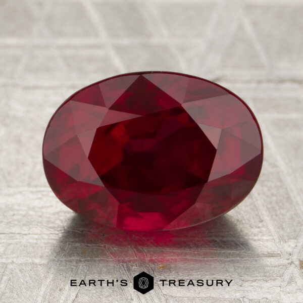 A 4.05-carat deep red Mozambique ruby (heated), cut in a faceted oval, displayed on a textured surface with the "EARTH'S TREASURY" logo and text below.