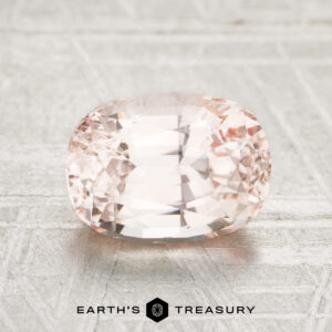 A faceted, oval-cut pale pink 2.24-Carat Ceylon Sapphire is displayed on a light textured surface with the Earth’s Treasury logo below.