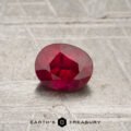 0.55-carat red Mozambique ruby (heated), oval-cut with visible inclusions, displayed on a textured surface above the text "EARTH'S TREASURY.