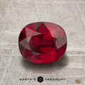 A 2.27-carat heated Mozambique ruby, cut in a faceted oval shape, is displayed on a textured metallic surface above the text "EARTH'S TREASURY.