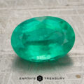 3.19-carat bright green Zambian emerald, oval-cut, displayed on a textured gray surface with the "EARTH'S TREASURY" logo at the bottom.