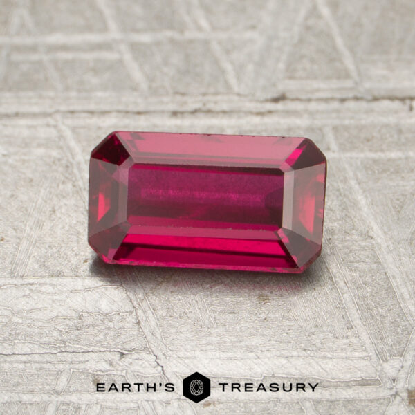1.02-Carat Mozambique Ruby (Heated) A rectangular, faceted 1.02-carat Mozambique ruby (heated) is displayed on a textured gray surface, with the text "EARTH'S TREASURY" at the bottom of the image.