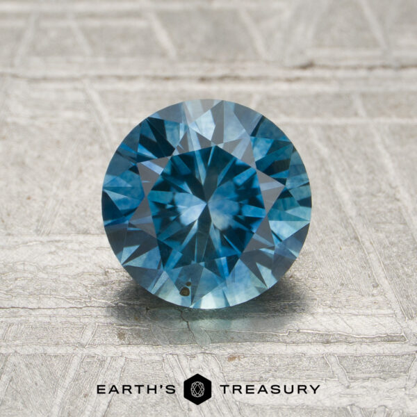 1.49-Carat Teal to Violet Color-Change Montana Sapphire (Heated) A 1.49-carat teal blue to violet color-change Montana sapphire with faceted cuts displayed on a textured light background, featuring the "Earth's Treasury" logo and text at the bottom.