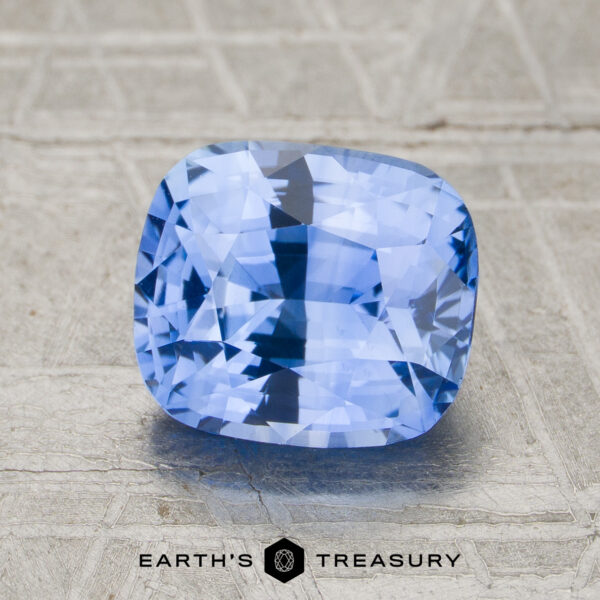 2.37-Carat Sky Blue Ceylon Sapphire (Heated) A 2.37-carat sky blue Ceylon sapphire (heated), faceted in a cushion cut, is displayed on a textured light surface with the "Earth's Treasury" logo at the bottom of the image.