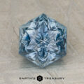 A hexagonal, blue gemstone with intricate, symmetrical faceting rests on a textured surface above the text "JM-001-252K.