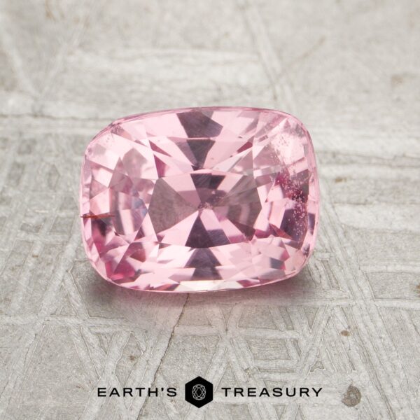JM-001-398JM-G A cushion-cut pink gemstone, product JM-001-398JM-G, rests on a textured gray surface with the "Earth's Treasury" logo below.
