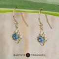 Gold earrings with blue gemstones and smaller clear stones hang side by side; the product name "Stacked from 40 images. Method=B (R=7,S=2)" and the text "Earth's Treasury" appear at the bottom of the image.