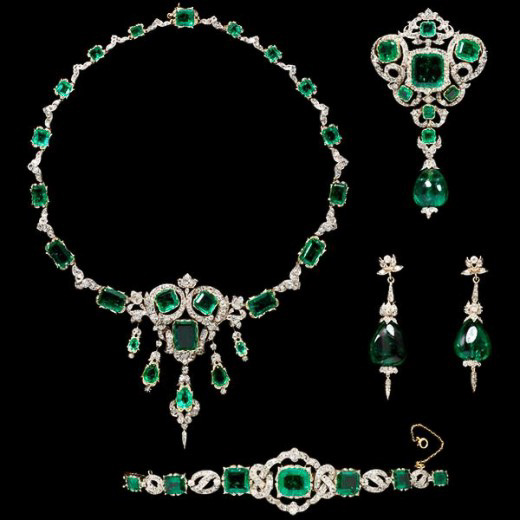 Introducing the elizabeth taylor suite-1200-BW: a refined diamond and emerald jewelry set showcasing a necklace, brooch, bracelet, and earrings—each adorned with striking green gemstones set in detailed silver or white gold. This collection embodies an elegant Emerald Guide for those desiring timeless sophistication.