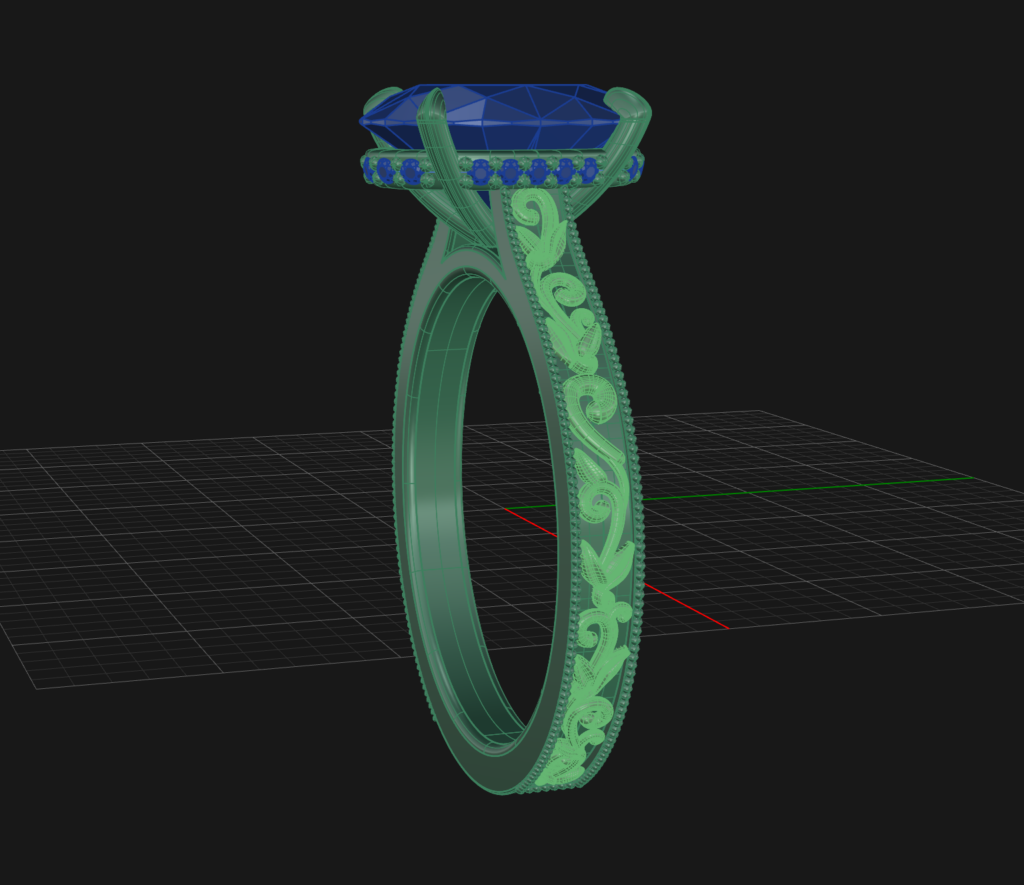 3D-rendered image of the CAD Filigree Example ring, showcasing ornate filigree patterns and intricate engraving on the band, with a large blue gemstone set in prongs, displayed on a dark grid background.