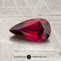 A faceted, pear-shaped 1.31-carat Mozambique Ruby (heated) in deep red rests on a textured, metallic surface with the “Earth’s Treasury” logo at the bottom.