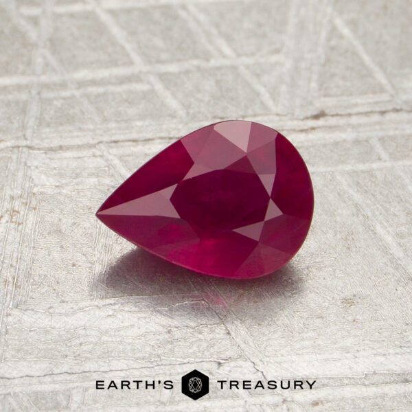 0.86-Carat Burmese Ruby (Heated) A pear-shaped, faceted 0.86-carat Burmese ruby (heated) is displayed on a textured surface with the logo and text “Earth’s Treasury” at the bottom.