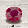 A 2.07-carat Mozambique ruby (heated), cut in an oval shape, is displayed on a light gray textured surface with “Earth’s Treasury” text below.