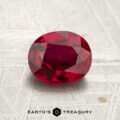 A 1.31-carat heated Mozambique ruby, expertly faceted in an oval cut, is displayed on a textured surface with the Earth’s Treasury logo beneath it.