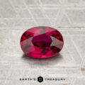 A 2.12-carat heated Madagascar ruby, cut in a faceted oval shape, rests on a textured metallic surface above the “EARTH’S TREASURY” name and geometric logo.