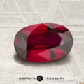 A 2.01-carat heated Mozambique ruby in an oval cut is displayed on a textured surface, with “Earth’s Treasury” appearing at the bottom of the image.