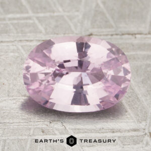 2.57-carat pale pink, oval-cut Ceylon sapphire (heated) displayed on a textured surface, with the “Earth’s Treasury” logo and name at the bottom of the image.