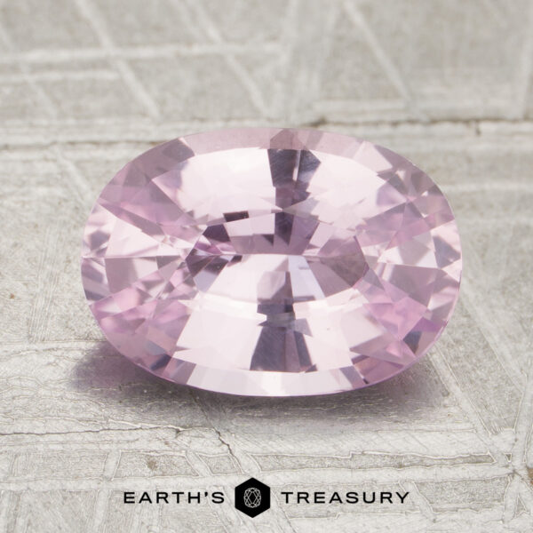 2.57-Carat Pale Pink Ceylon Sapphire (Heated) 2.57-carat pale pink, oval-cut Ceylon sapphire (heated) displayed on a textured surface, with the “Earth’s Treasury” logo and name at the bottom of the image.