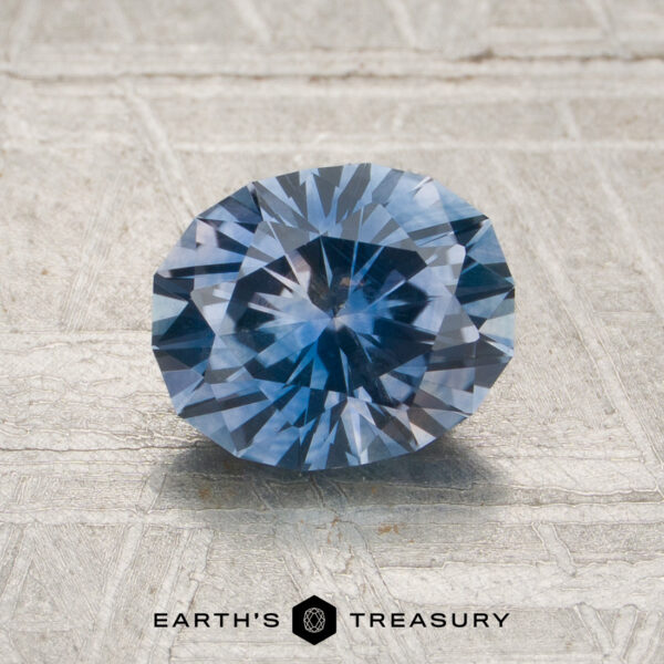 1.49-Carat Rich Sky Blue Montana Sapphire (Heated) A 1.49-carat, medium blue faceted Montana sapphire (heated) is positioned on a textured, light-colored surface with the Earth’s Treasury logo and text below.