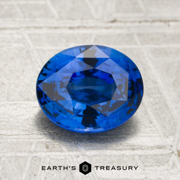 2.04-Carat Royal Blue Ceylon Sapphire (Heated) A 2.04-carat Royal Blue Ceylon Sapphire (heated) in a faceted oval cut rests on a textured light surface, with the words “Earth’s Treasury” displayed underneath.