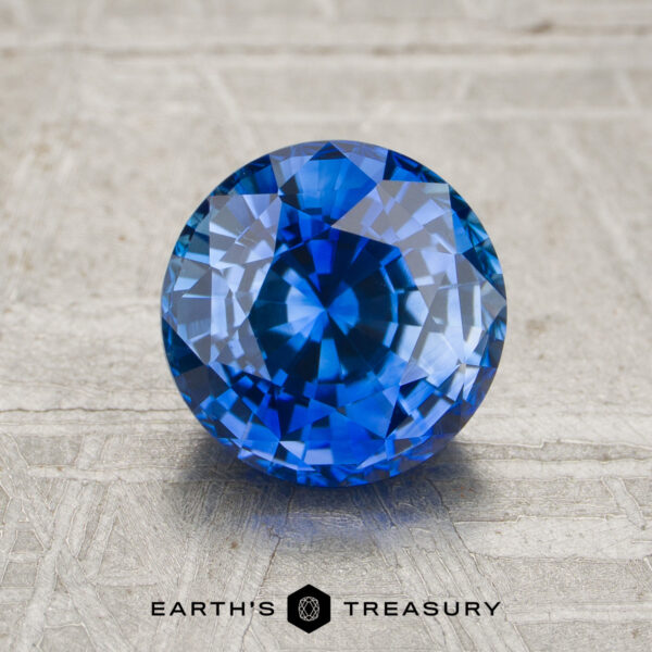 1.91-Carat Rich Blue Ceylon Sapphire (Heated) A 1.91-carat rich blue Ceylon sapphire (heated) with intricate facets is displayed on a textured light surface, with the text “EARTH’S TREASURY” beneath the stone.