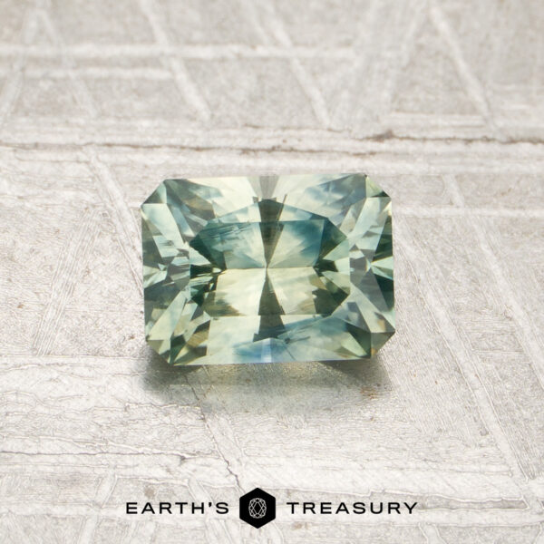 0.96-Carat Mint Green Montana Sapphire (Heated) A 0.96-carat, rectangular, faceted mint green Montana sapphire (heated) is displayed on a textured pale background, with the words “EARTH’S TREASURY” beneath it.