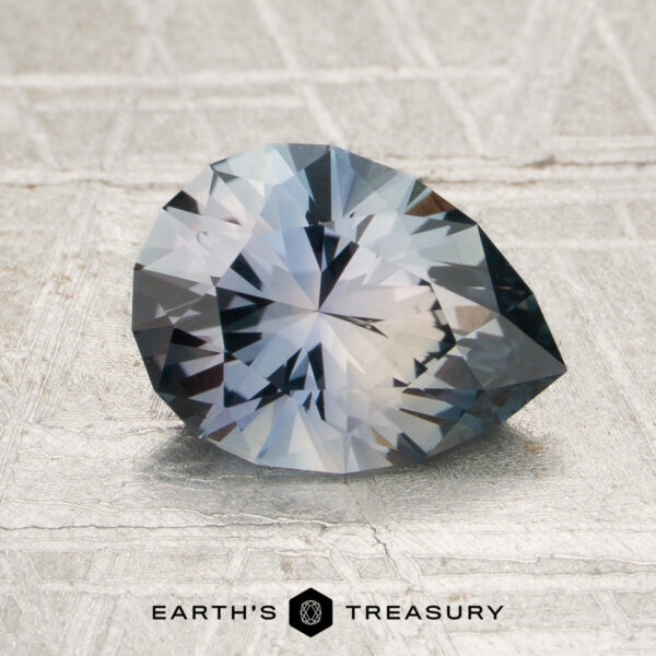 1.89-Carat Blue-Gray Montana Sapphire (Heated) A 1.89-carat blue-gray Montana sapphire (heated) rests on a textured surface, with the Earth’s Treasury logo displayed at the bottom of the image.