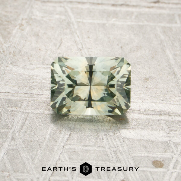 0.97-Carat Mint Green Montana Sapphire (Heated) A rectangular, pale mint green faceted gemstone—identified as a 0.97-carat Mint Green Montana Sapphire (Heated)—is displayed on a light textured surface. The logo and text “EARTH’S TREASURY” appear at the bottom of the image.